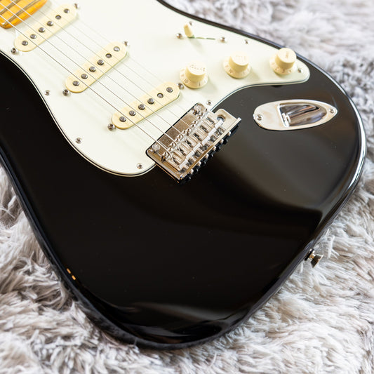 Close-up of a black Fender Stratocaster two-point synchronized tremolo bridge with chrome saddles and the vibrato arm installed