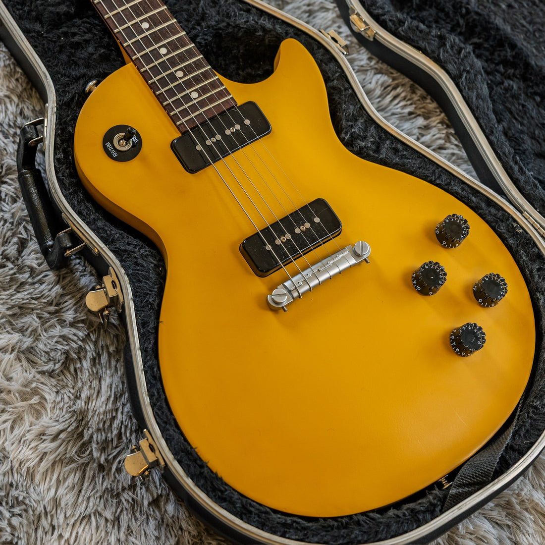 Used Gibson Les Paul in gold sitting in an open hardshell case, brought in to a guitar shop to sell or trade