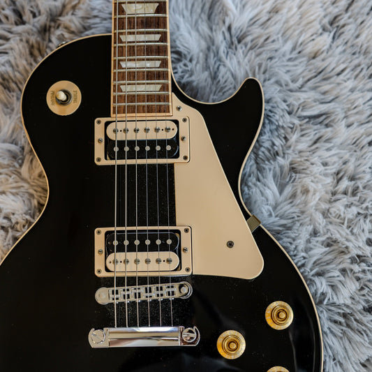 Close-up of two uncovered humbucker pickups on a black Gibson Les Paul