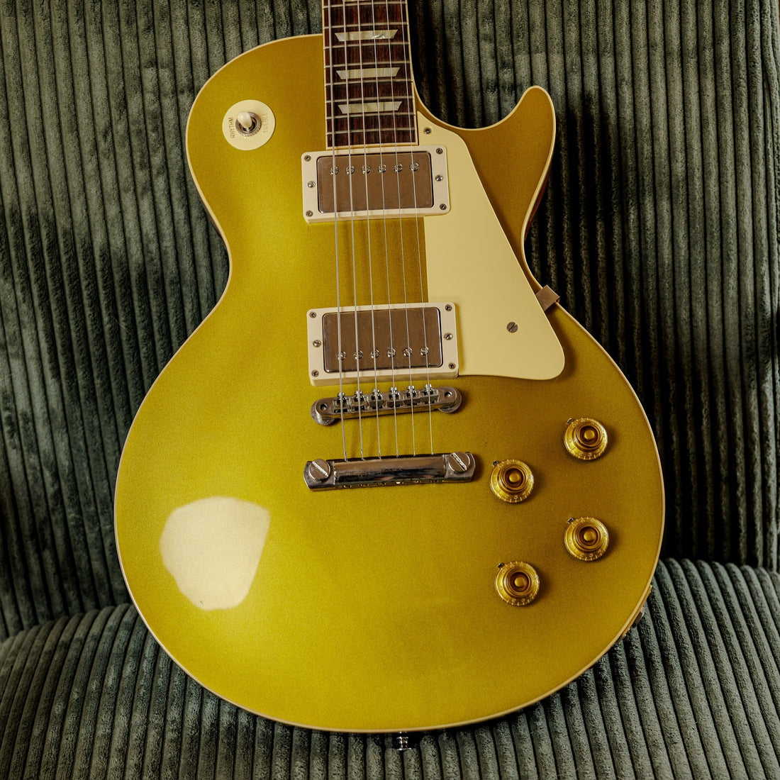 Gibson Custom Shop R7 1957 Les Paul Standard Reissue goldtop resting on a green chair